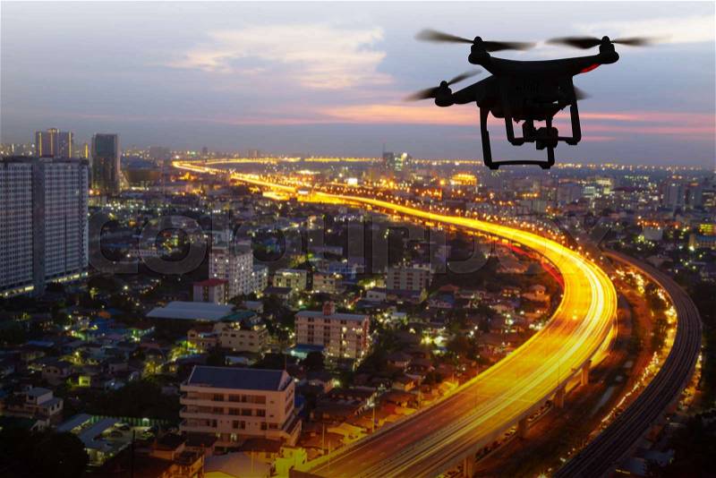 Silhouette of drone flying above city at sunset, stock photo