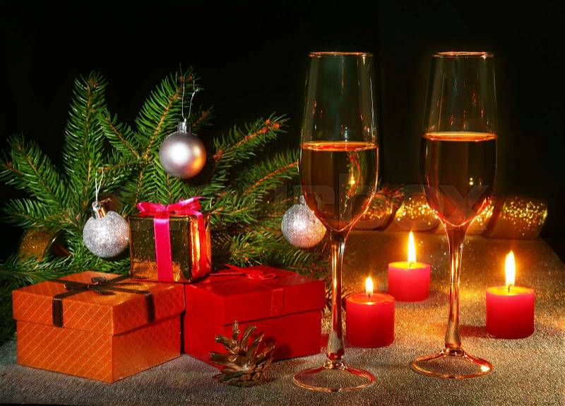 Christmas composition with Glass of sparkling champagne wine or cognac, christmas candles, colorful balls, gift box and tree on a sparkling background. New Year decoration, stock photo