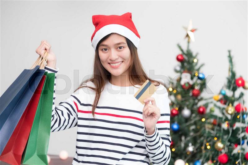 Happy Asia woman use credit card buy Christmas gift in shopping bag at home in party,Holiday online shopping, stock photo