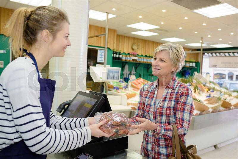 Woman buying groceries at farmers market stand, stock photo