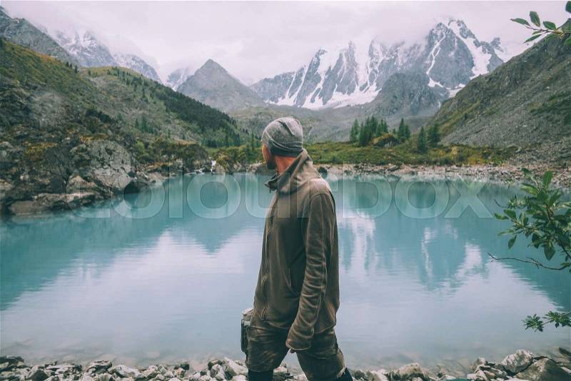 Side view of man looking at majestic calm mountain lake in Altai, Russia, stock photo