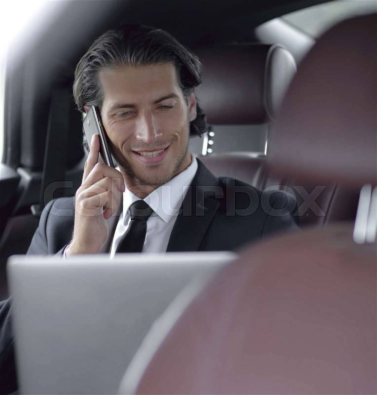Businessman in his car talking on the smartphone, stock photo