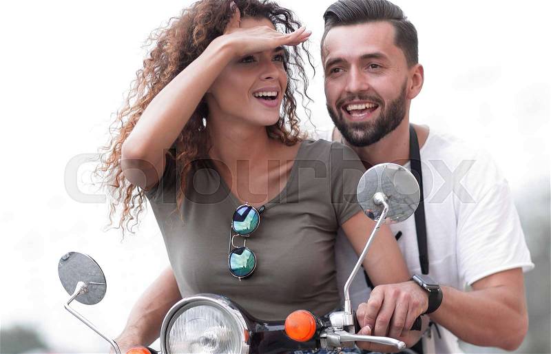 Beautiful young couple is smiling while riding a scooter, stock photo
