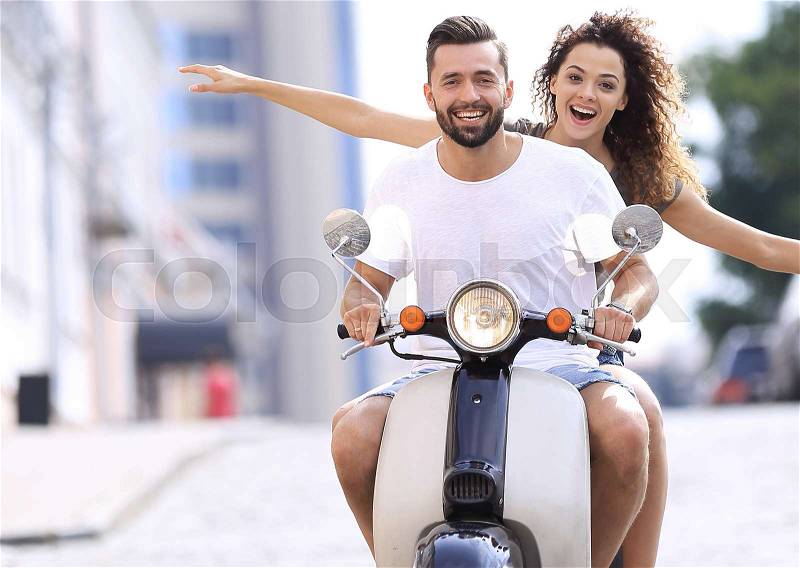 Happy young couple riding a scooter in the city on a sunny day, stock photo