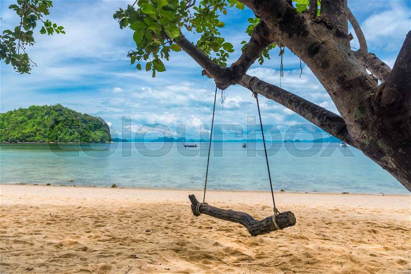 Close-up of a swing on a tree on a sandy pyramid on the background of the sea, Thailand, stock photo