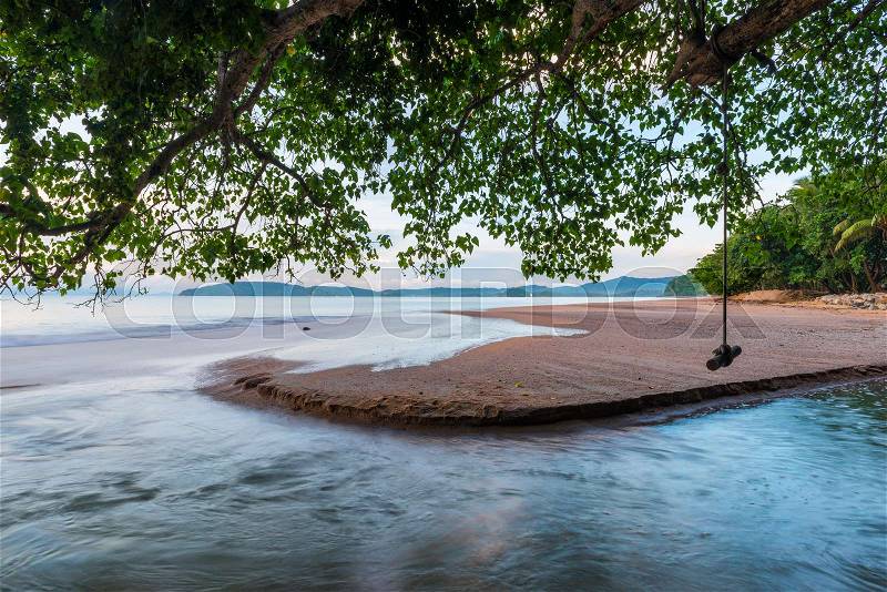 River flowing into the sea under the foliage of a tree, a view of the beach of Thailand, stock photo