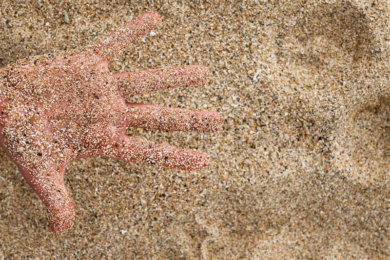 A caucasian hand in the sand on the beach while resting on vacation, stock photo
