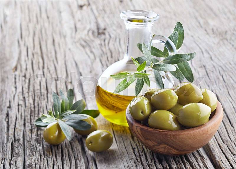 Virgin olive oil and green olives on wooden board, stock photo