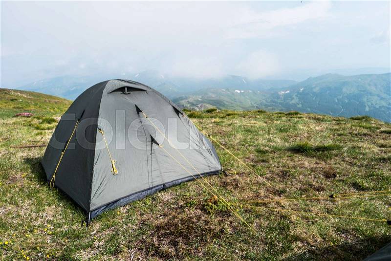 Grey tourist tent in camp among meadow in the mountain. Camping outdoor, grey tent in mountains, stock photo