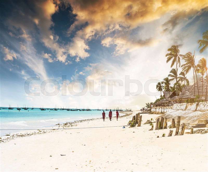 Picturesque landscape with ocean beach and african village and palms at sunset, stock photo