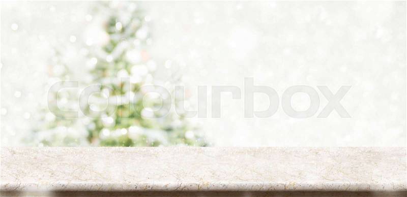 Empty cream marble table top with abstract muted blur christmas tree and snow fall background with bokeh light,Holiday backdrop,Mock up banner for display or montage of product, stock photo