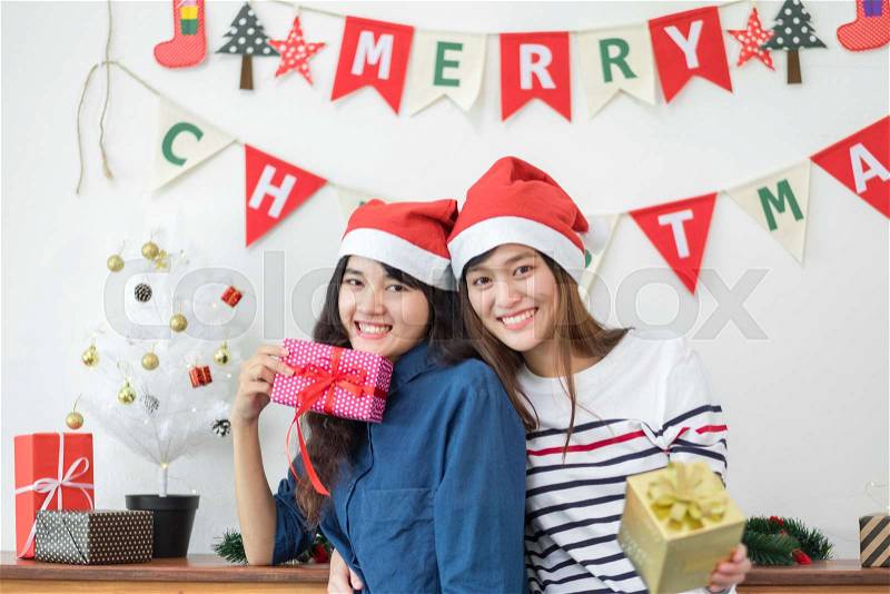 Asia girl friends wear santa hat in merry christmas and new year party exchange red gift box each other with smiling face,Xmas gift giving,Lovely lesbian couple lifestyle, stock photo