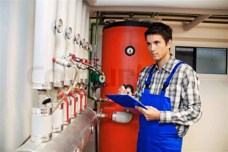 Young engineers in heating boiler heating system with, stock photo