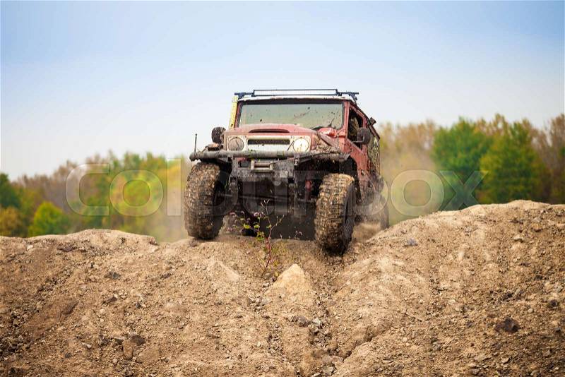 Classic red off road car moving on dirt terrain, stock photo