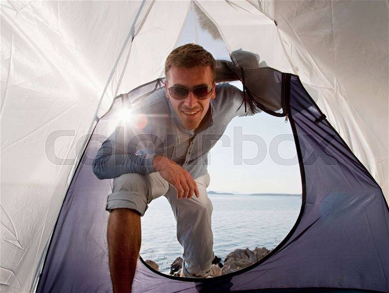 Man entering tent by sea, stock photo