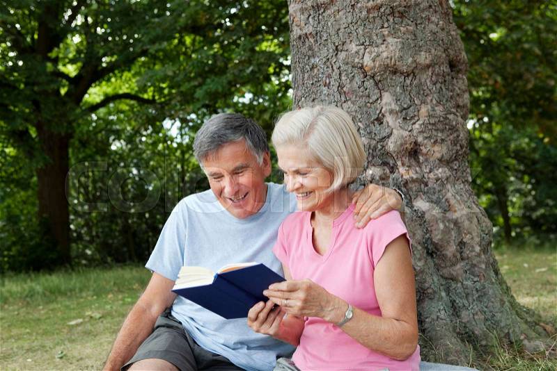 Couple sharing book in park, stock photo