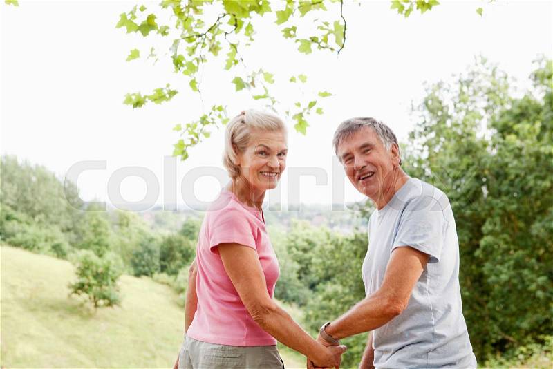 Mature couple holding hands looking back, stock photo