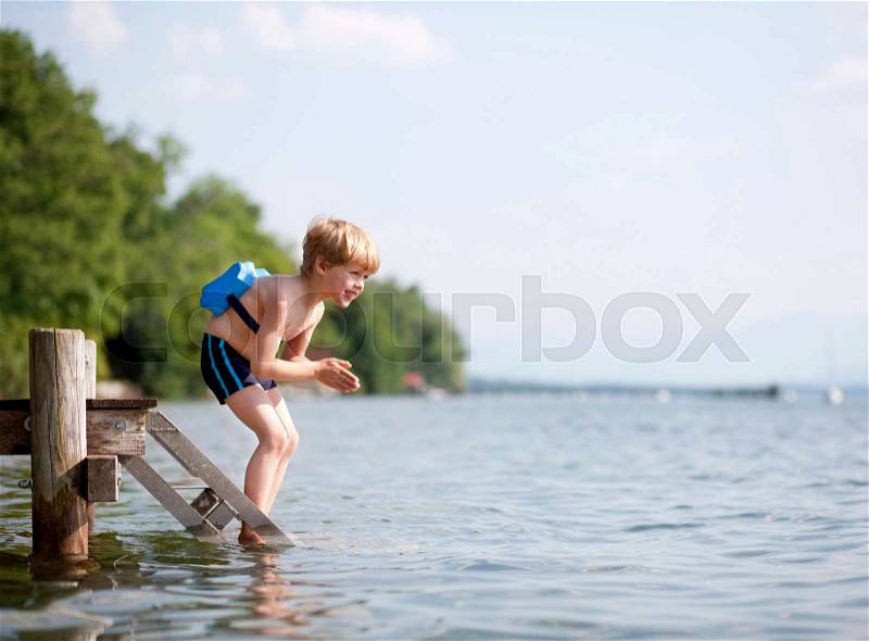 Boy jumping in water with swimming belt, stock photo