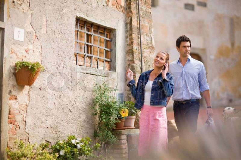 Man and woman walking past house, stock photo