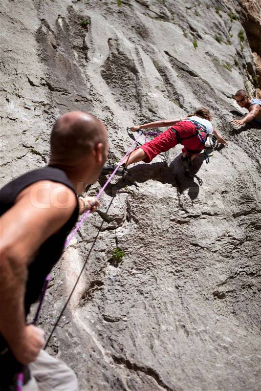Rock climber securing partner, stock photo