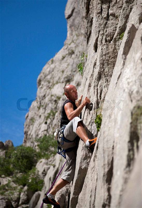 Rock climber climbing rock face, stock photo