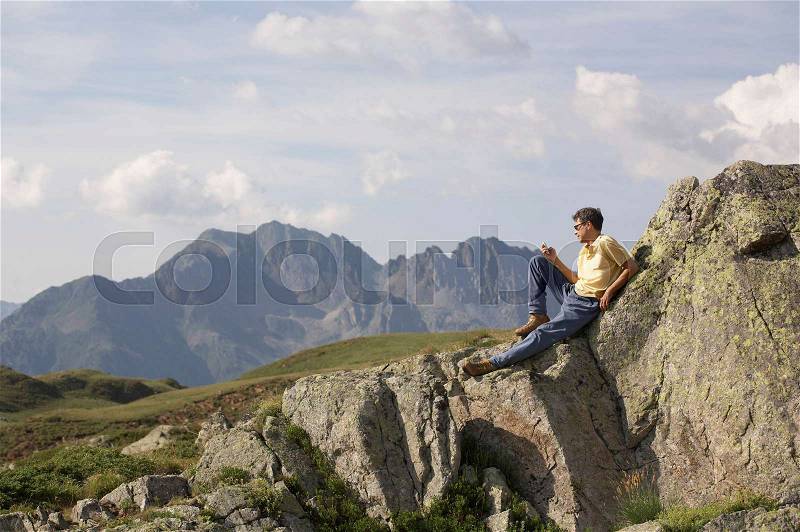 Man on phone looking over mountains, stock photo