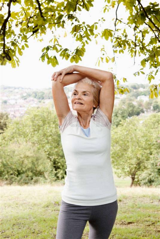 Mature woman stretching arms above head, stock photo