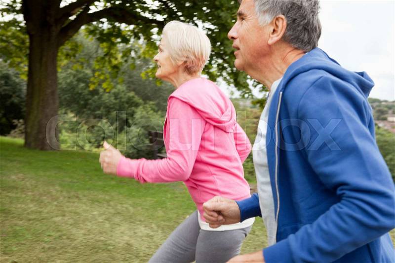 Mature couple jogging in park, stock photo