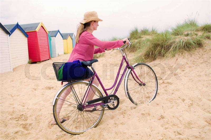 Women pushes bicycle over beach, stock photo