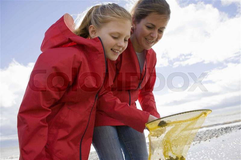 Mother and daughter looking into fishnet, stock photo