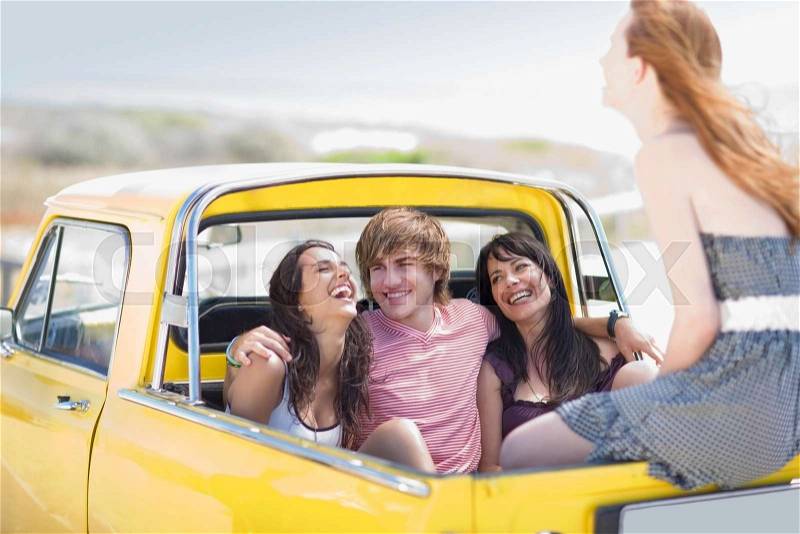 Young people sitting on back of pickup, stock photo