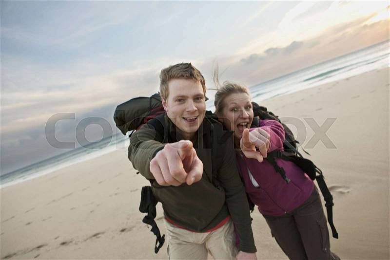 Backpacking couple pointing at camera, stock photo
