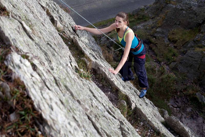 Woman climbing a rock face, stock photo