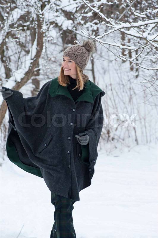 Woman in heavy cape walking in snow, stock photo