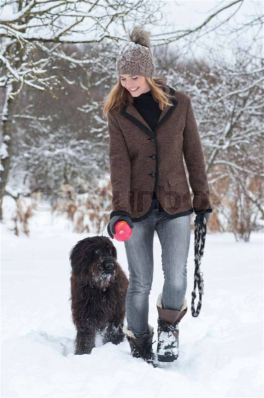 Woman walking dog in snow, stock photo