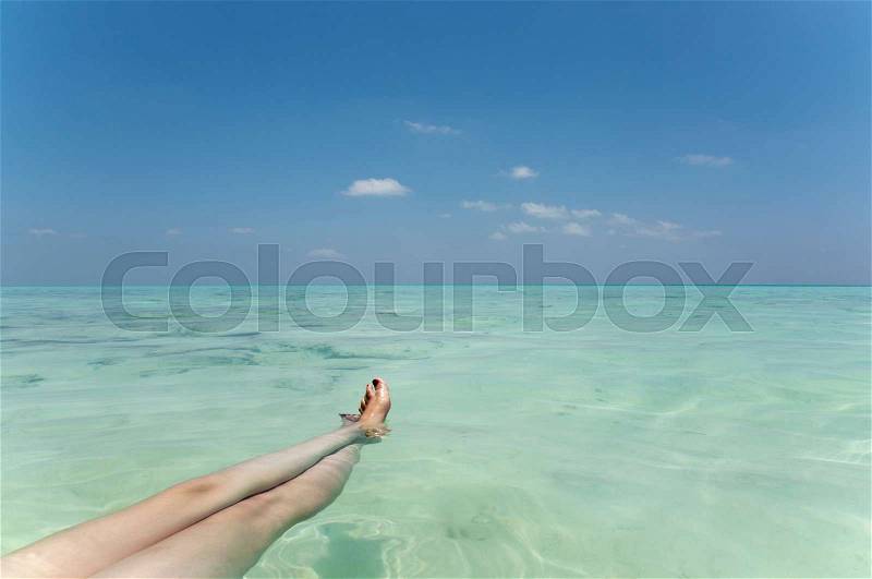 Woman?s legs floating in tropical sea, stock photo
