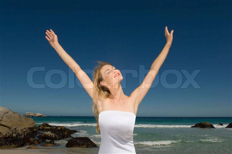 Woman with arms outstretched on beach, stock photo
