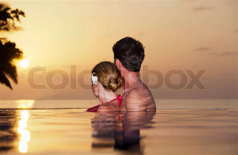 Couple embracing in infinity pool, stock photo