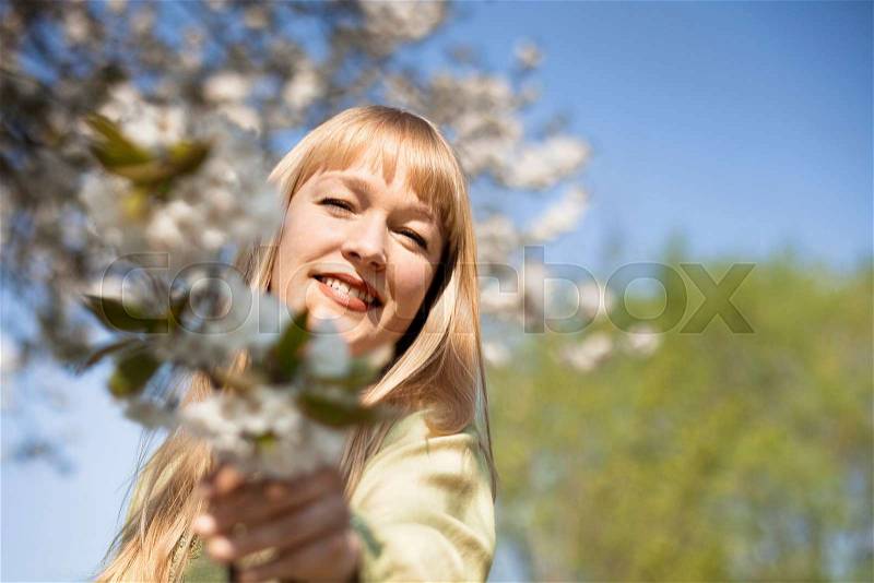 Woman offering flowers outdoors, stock photo