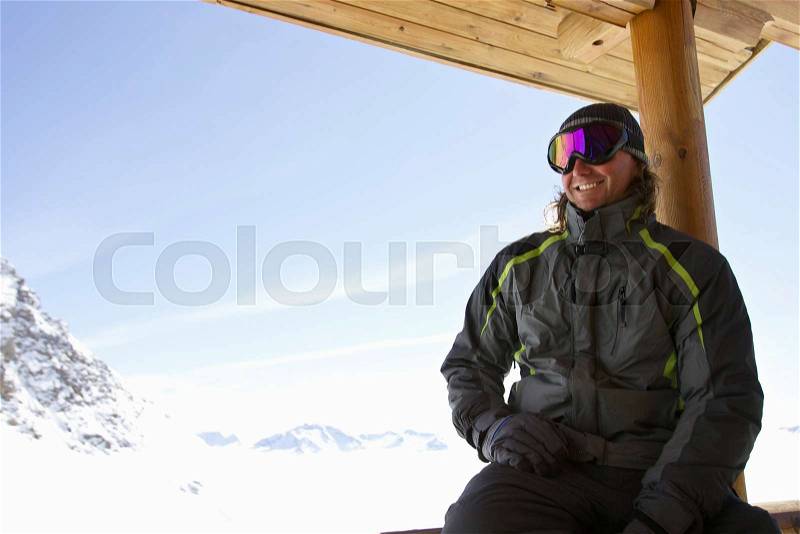 Man relaxing on ski lodge balcony, stock photo