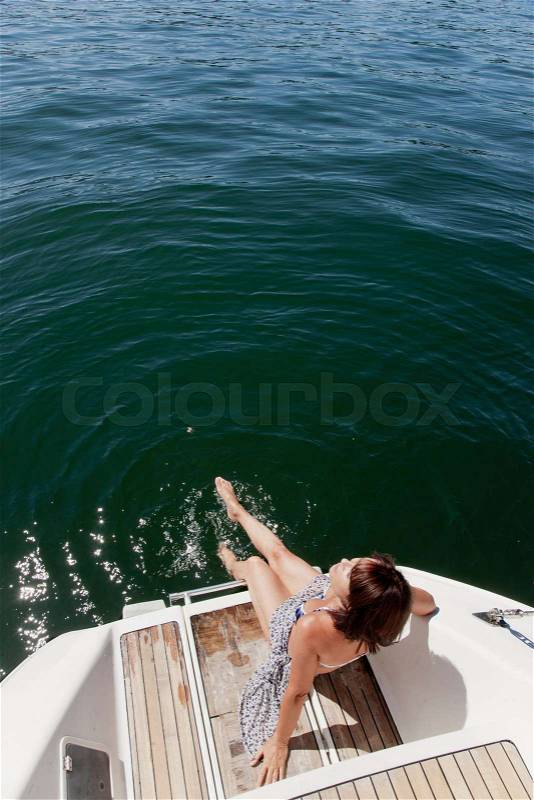 Woman dangling feet from sailboat, stock photo