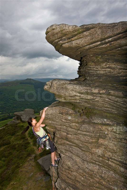 Rock climber scaling steep rock face, stock photo