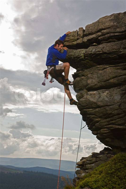 Rock climber scaling steep rock face, stock photo