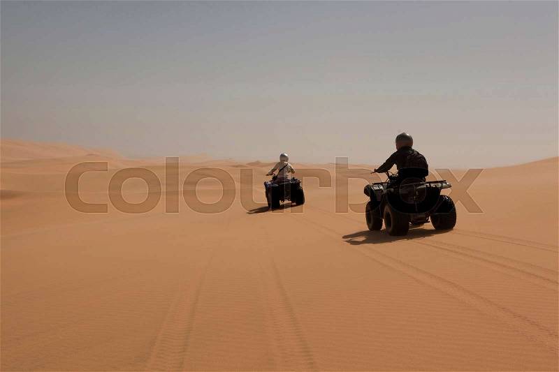 People driving four wheelers on sand, stock photo