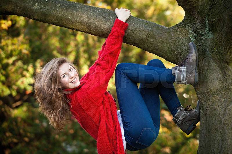 Teenage girl climbing tree in park, stock photo