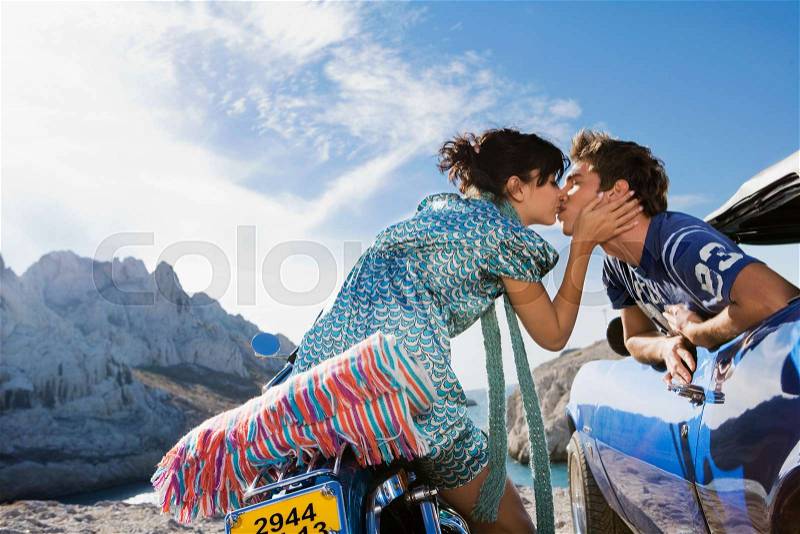 Man in car woman on motorbike kissing, stock photo