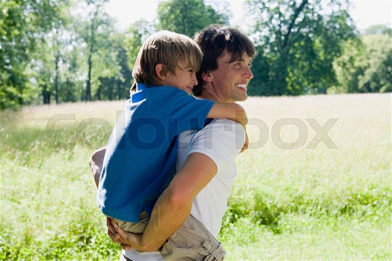 Father giving son a piggyback, stock photo