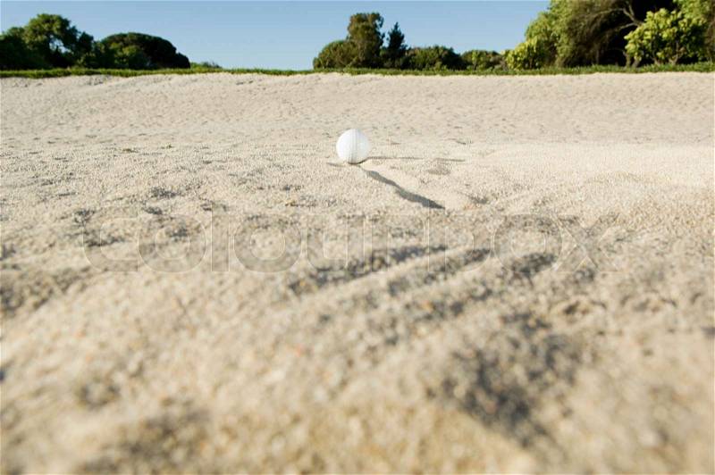 A golf ball in a sand trap, stock photo