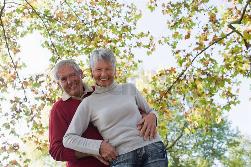 Senior couple hugging near trees, stock photo