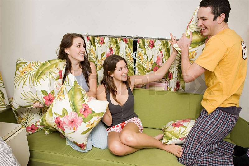 Teenage friends having a pillow fight, stock photo
